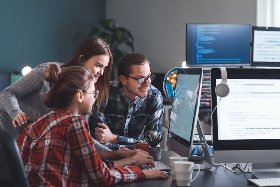 Group of three discussing code on a computer screen